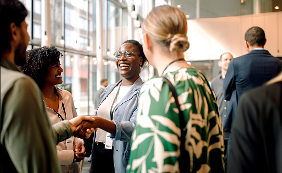 Plusieurs personnes échangent dans un cadre professionnel, avec le sourire et un engagement dans la conversation.